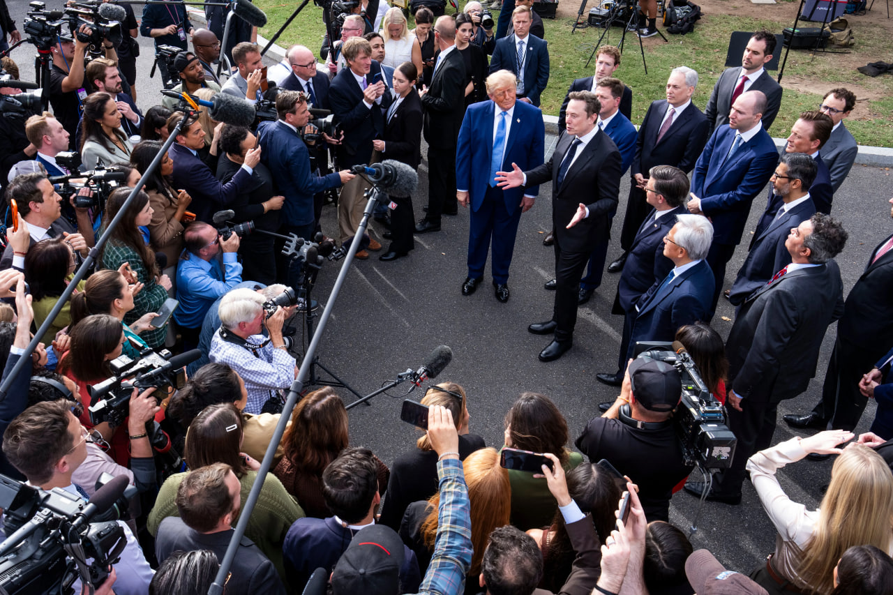 Elon Musk and Donald Trump surrounded by a scrum of reporters and cameras